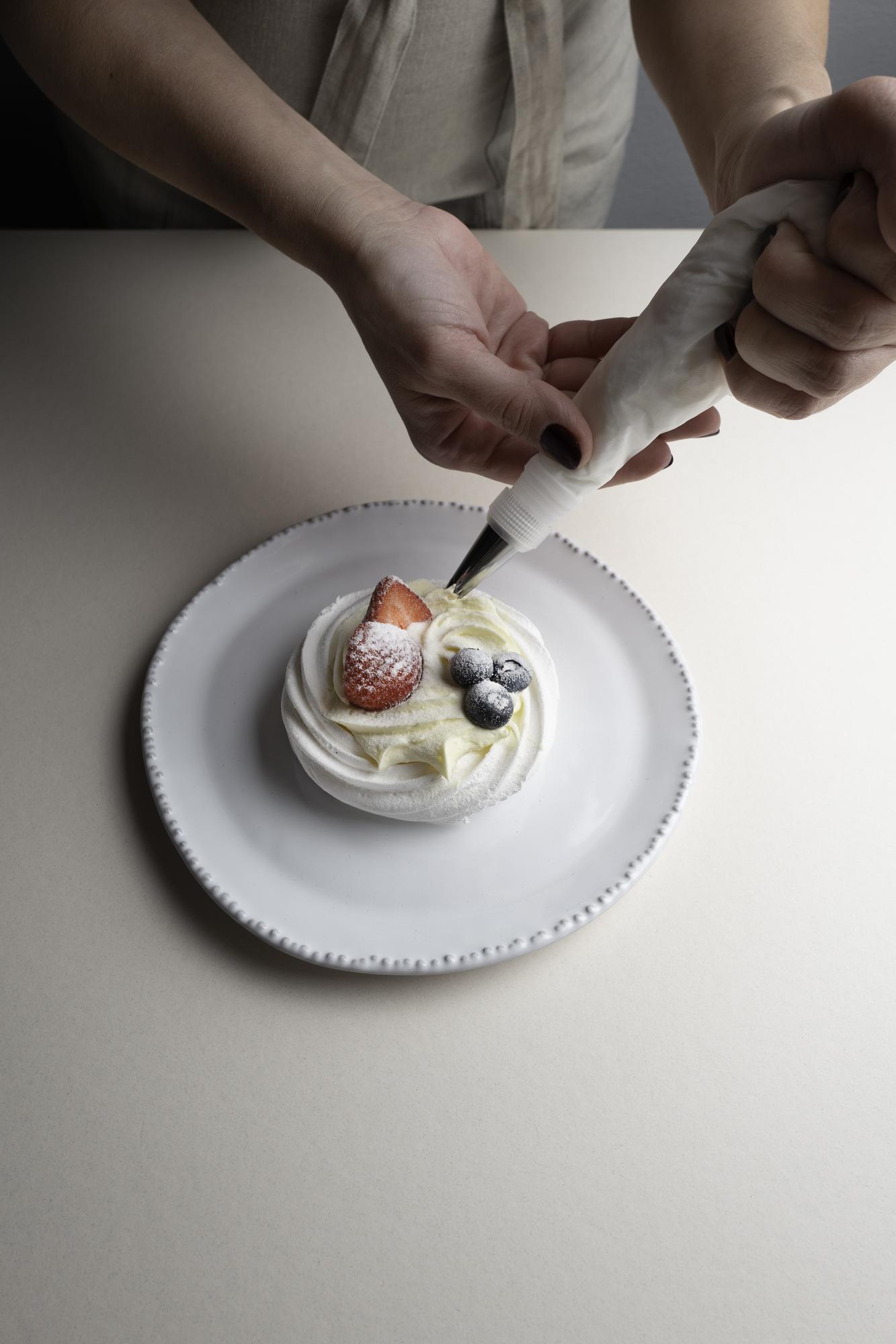 Hands plating dessert in studio lighting